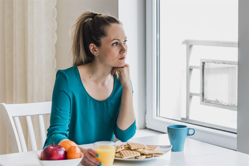 Femeie tânără la micul dejun, reflectând la obiceiurile ei alimentare